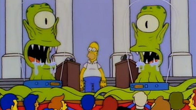 A screenshot from The Simpsons shows two large aliens near Homer. 