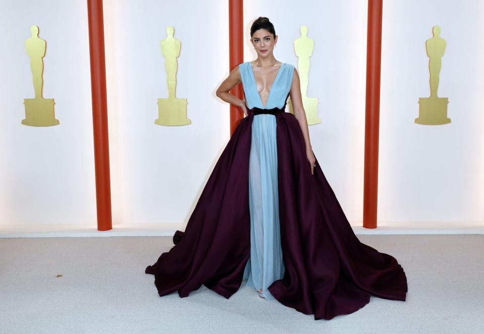 Monica Barbaro in a light blue gown with darker wrap-around, floor length skirt.