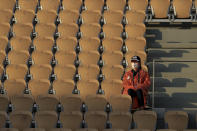 A stadium employee sits amidst rows of empty seats at center court Philippe Chatrier during the first round match of the French Open tennis tournament between Spain's Rafael Nadal and Egor Gerasimov of Belarus at the Roland Garros stadium in Paris, France, Monday, Sept. 28, 2020. (AP Photo/Michel Euler)