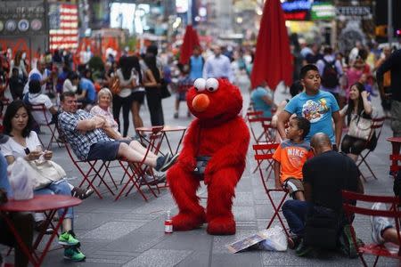 Jorge, an immigrant from Mexico, dressed as the Sesame Street character Elmo rests in Times Square, New York July 29, 2014. REUTERS/Eduardo Munoz