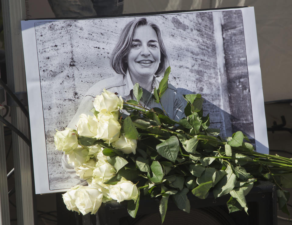 FILE - In this Saturday, April 5, 2014 file photo, roses lay in front of a picture of the Associated Press photographer Anja Niedringhaus, 48, who was killed April 4, 2014 in Afghanistan, in Paris. Fellow officers say the Afghan police commander who killed Niedringhaus and wounded reporter Kathy Gannon seemed a calm, pious man who may have come under the influence of Islamic fundamentalists calling for vengeance against foreigners over drone strikes. (AP Photo/Michel Euler, File)