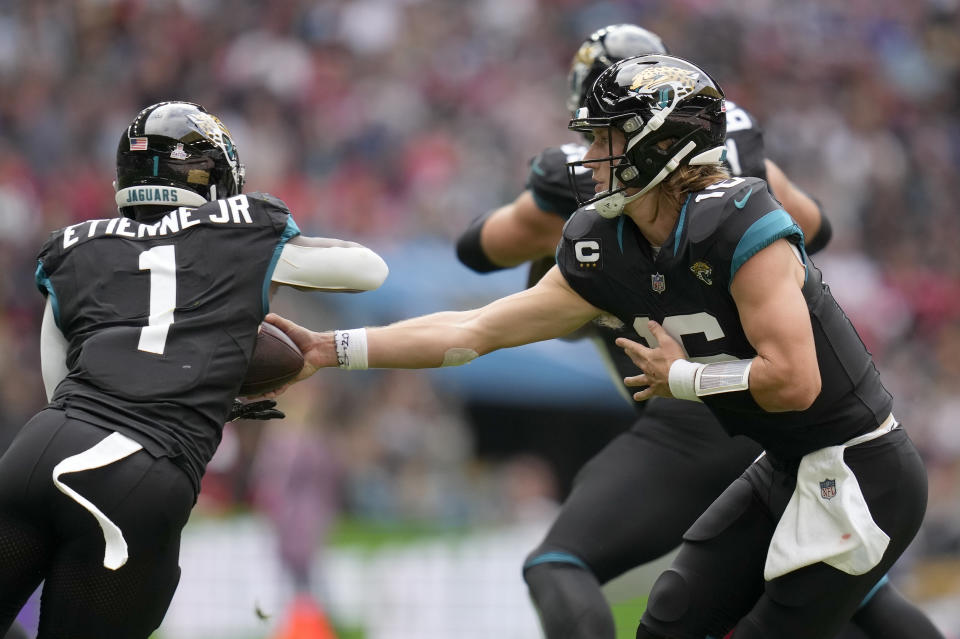 Jacksonville Jaguars quarterback Trevor Lawrence (16) hands off to Jaguars running back Travis Etienne Jr. (1) during the first quarter of an NFL football game between the Atlanta Falcons and the Jacksonville Jaguars at Wembley stadium in London, Sunday, Oct. 1, 2023. (AP Photo/Kirsty Wigglesworth)