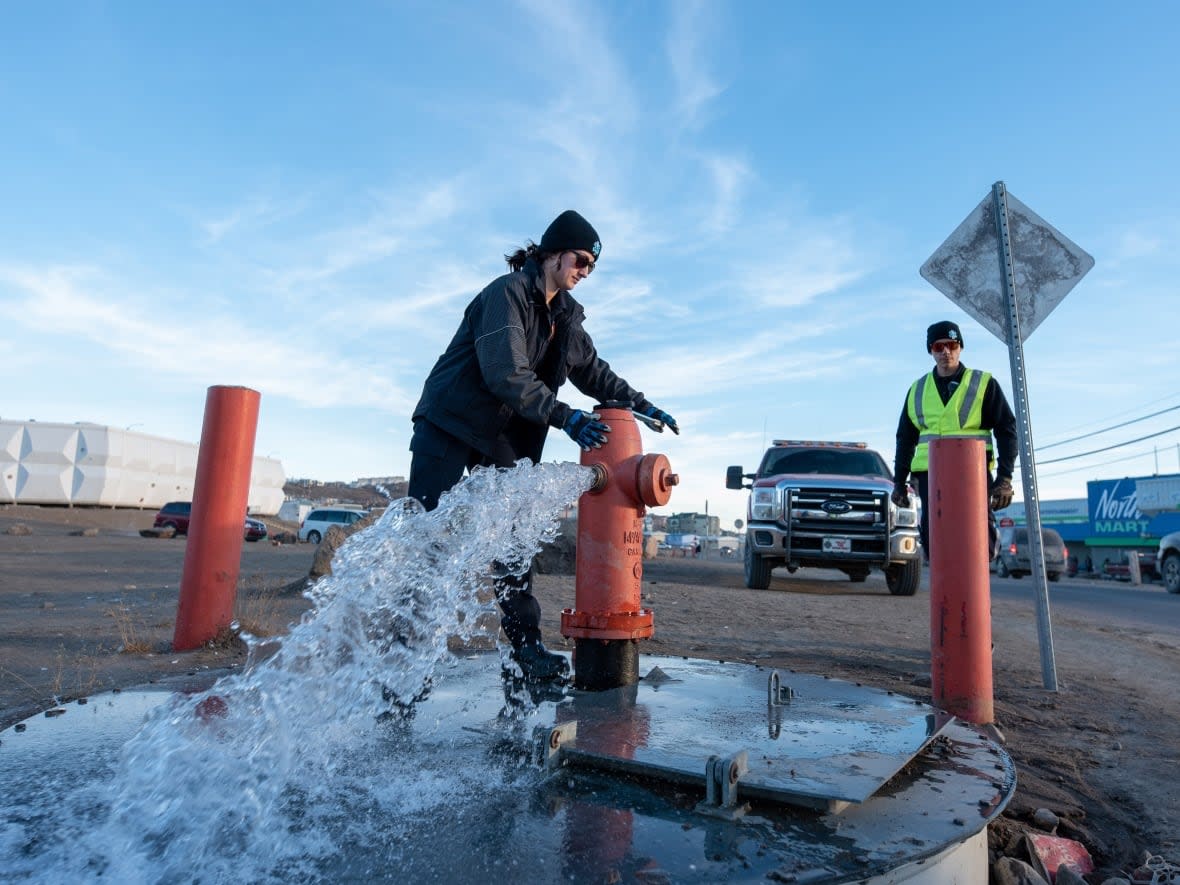 Members of the Iqaluit Fire Department assist with flushing the city's water pipes in Iqaluit on Wednesday. Flushing will wrap up Thursday, the city said. (Dustin Patar/The Canadian Press - image credit)