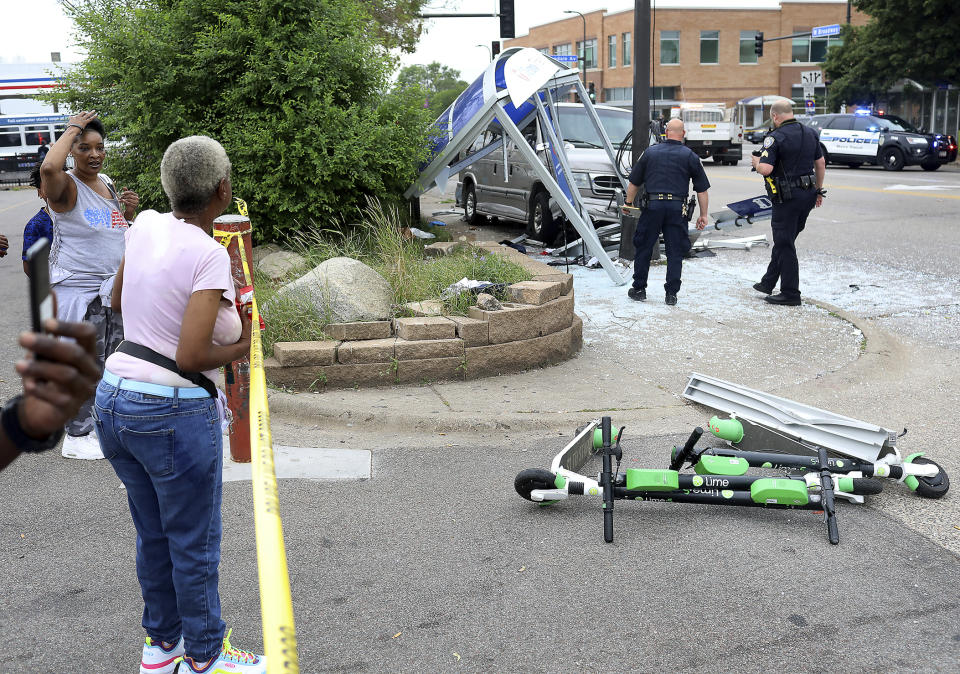 Sade Adams of Maplewood watches the scene of a crash from the parking lot of a nearby Cub Foods in Minneapolis, Minn. At least six people were hurt, including three critically, when a van slammed into a crowded bus stop shelter in north Minneapolis. All six were transported to hospitals. Metro Transit spokesman Howie Padilla says police took the driver of the van into custody following the crash about 9:30 a.m. Tuesday, July 9, 2019. (David Joles/Star Tribune via AP)