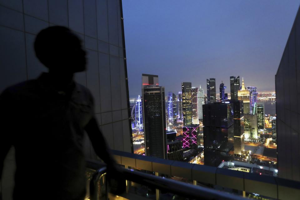 FILE - A lifeguard for a hotel swimming pool looks at the West Bay district, populated by many modern high rises, in Doha, Qatar. Saturday, May 4, 2019. For decades, Doha has flung open its doors to Taliban warlords, Islamist dissidents, African rebel commanders and exiles of every stripe. (AP Photo/Kamran Jebreili, File)