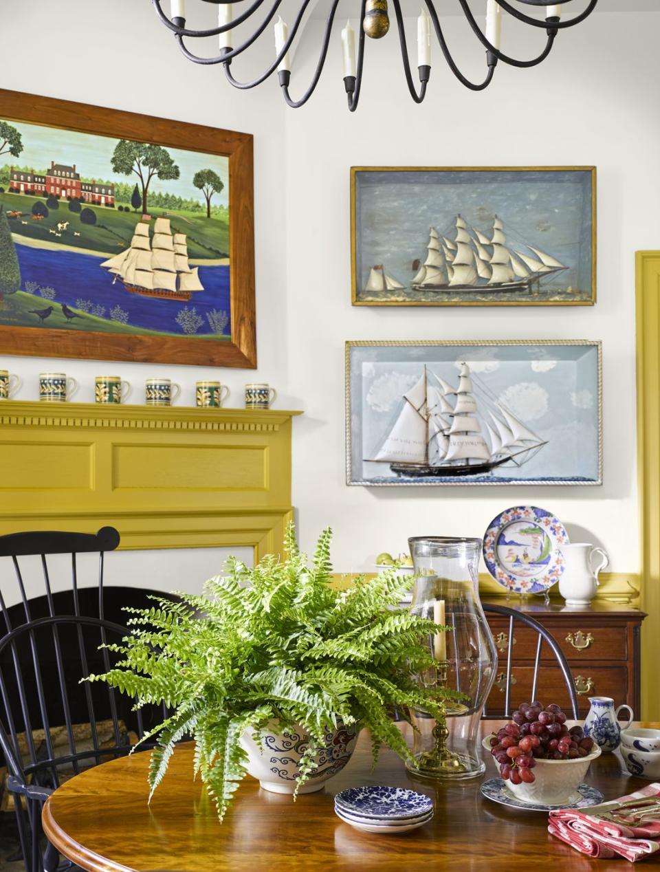 colonial inspired dining room with yellow trim, ship paintings adorn the wall