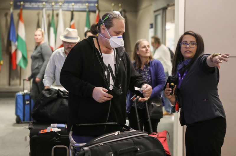FILE PHOTO: A ticket agent helps travelers arriving on a flight from Frankfurt, Germany before travel restrictions are enacted hours later on flights from Europe entering the U.S. because of concerns of the novel coronavirus at the Denver International Air