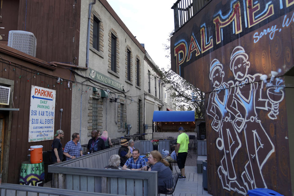 Patrons sit on the back patio of Palmer's Bar, which is next door to Dar Al-Hijrah mosque in Minneapolis, on Thursday, May 12, 2022. The Islamic call to prayer, or adhan, can be heard three times a day from the bar's patio. (AP Photo/Jessie Wardarski)