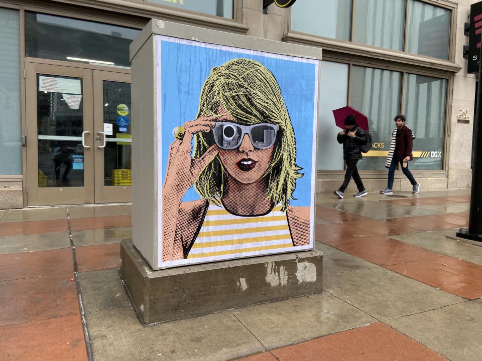 Mike Dellaria's wheat paste artwork on Main Street. The piece depicts Taylor Swift watching the solar eclipse with the Rochester skyline in the background.