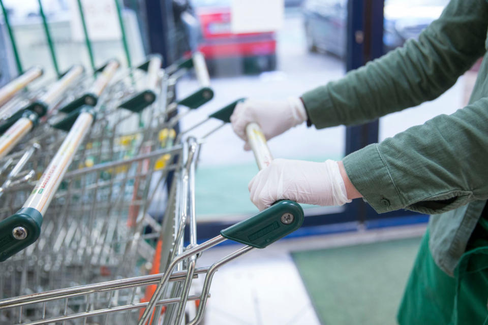 A woman with disposable gloves drives a shopping trolley. Source: Getty Images