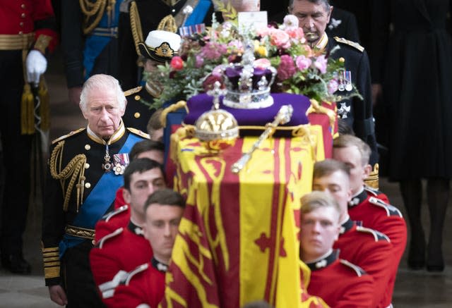 The King next to the coffin of Queen Elizabeth II, draped in the Royal Standard with the Imperial State Crown and the Sovereign’s orb and sceptre, as it is carried out of Westminster Abbey after her State Funeral.