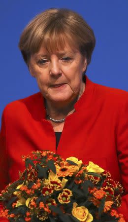 German Chancellor and leader of the conservative Christian Democratic Union party CDU Angela Merkel receives flowers after she was re-elected as chairwoman at the CDU party convention in Essen, Germany, December 6, 2016. REUTERS/Kai Pfaffenbach