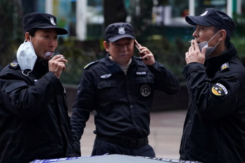 Security guards smoke at a the Nanjing Pedestrian Road, a main shopping area, in Shanghai