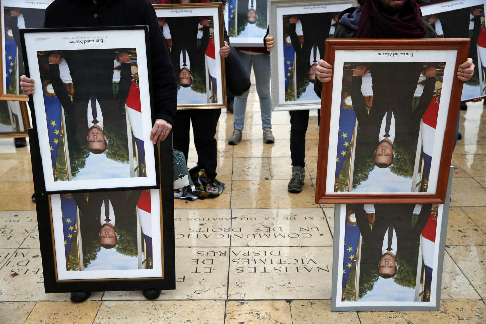 A hundred activists hold portraits of President Emmanuel Macron to urge France to take action during the U.N. COP 25 climate talks in Madrid, during a gathering at Place du Trocadero facing the Eiffel Tower in Paris, Sunday, Dec. 8, 2019. Environmental activists around France have removed President Emmanuel Macron's official portrait from town halls around the country in an unusual protest movement aimed at pushing him to do more to slow climate change. (AP Photo/Francois Mori)