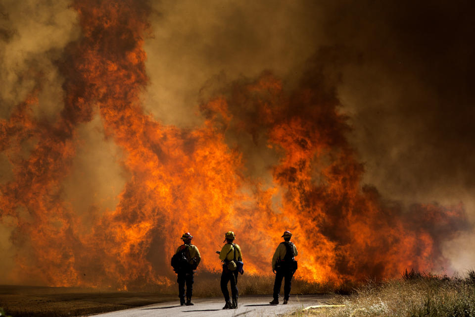 Firefighters watch as flames flare at the Apple Fire in Cherry Valley, Calif., Saturday, Aug. 1, 2020. A wildfire northwest of Palm Springs flared up Saturday afternoon, prompting authorities to issue new evacuation orders as firefighters fought the blaze in triple-degree heat.(AP Photo/Ringo H.W. Chiu)