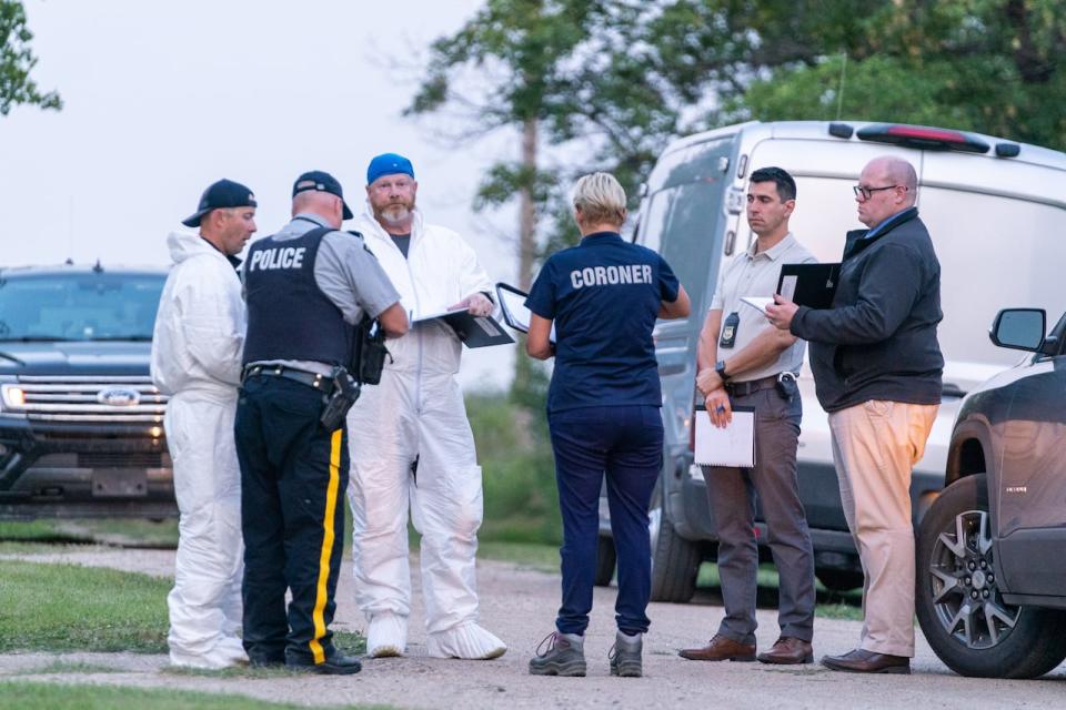 Des enquêteurs portant un équipement de protection examinent le sol sur la scène du crime à Weldon, en Saskatchewan, près de la nation crie de James Smith, où Myles Sanderson s'est déchaîné en 2022. (Heywood Yu/La Presse canadienne – crédit image)