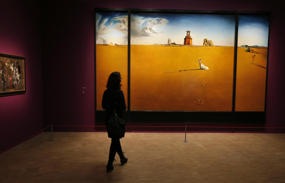 In this photo taken Monday Nov. 19, 2012, a women looks at the painting 'Paysage avec jeune fille sautant a la corde, 1936' by Spanish artist Salvador Dali (1904-1989) during the presentation to the press of the exhibition "Dali" at the Centre Pompidou modern art museum, in Paris. A major retrospective of Salvador Dali in Paris aims to rewrite the art history books, reconciling for the first time the last decades of his life when he was accused of money-making self-publicity through numerous television appearances with his earlier, respected Surrealist period. (AP Photo/Francois Mori)