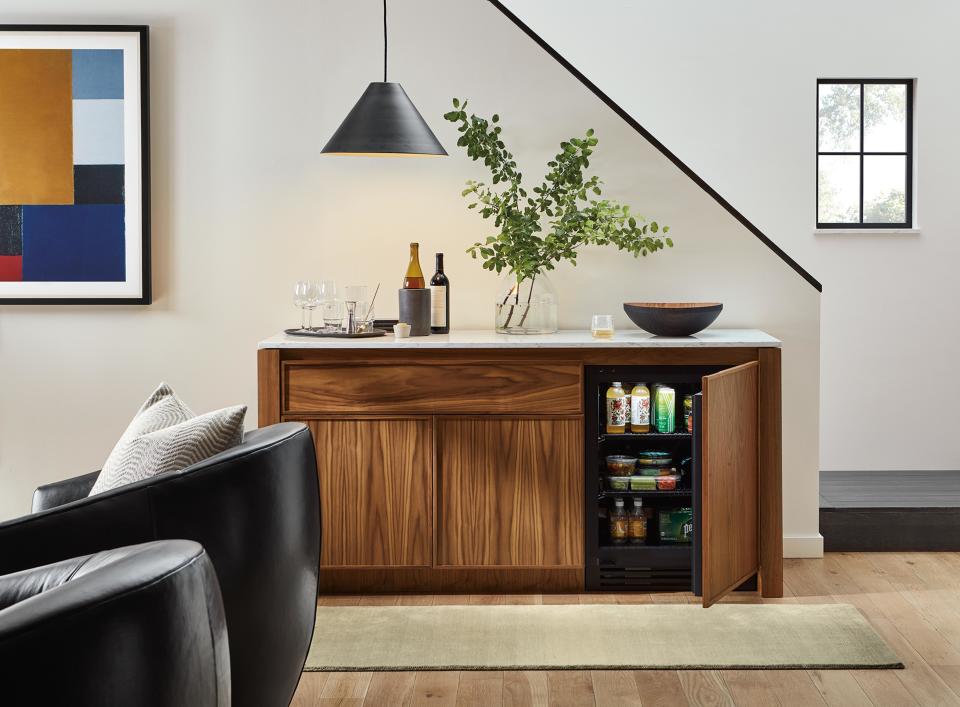 This image released by Amherst Cabinets shows a walnut cabinet that can work as a resting spot for a TV, books or art objects, while the interior is a handy fridge. The top comes in a variety of colors in granite or quartz. (Amherst Cabinets via AP)