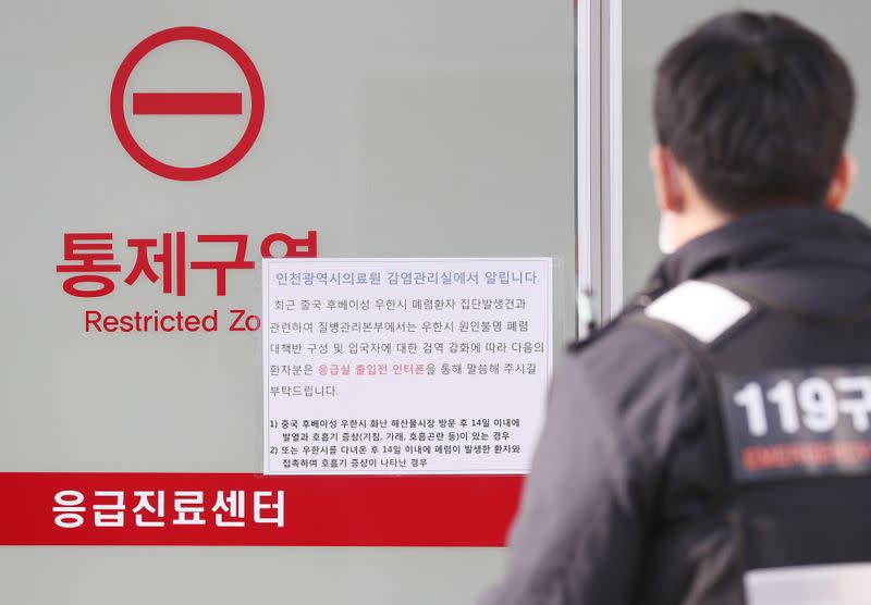 A rescue worker walks past a notice about new coronavirus that has broken out in China, at a hospital where a Chinese woman who flew from Wuhan, China, and has been confirmed its first case of a new coronavirus, is isolated, in Incheon