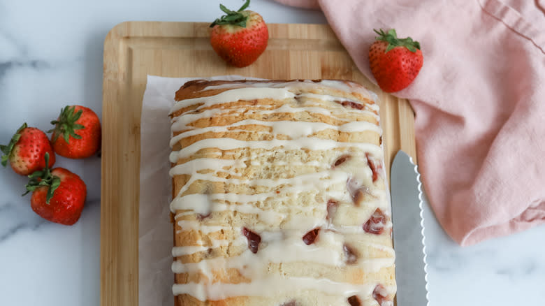 strawberry bread loaf with icing on wood board