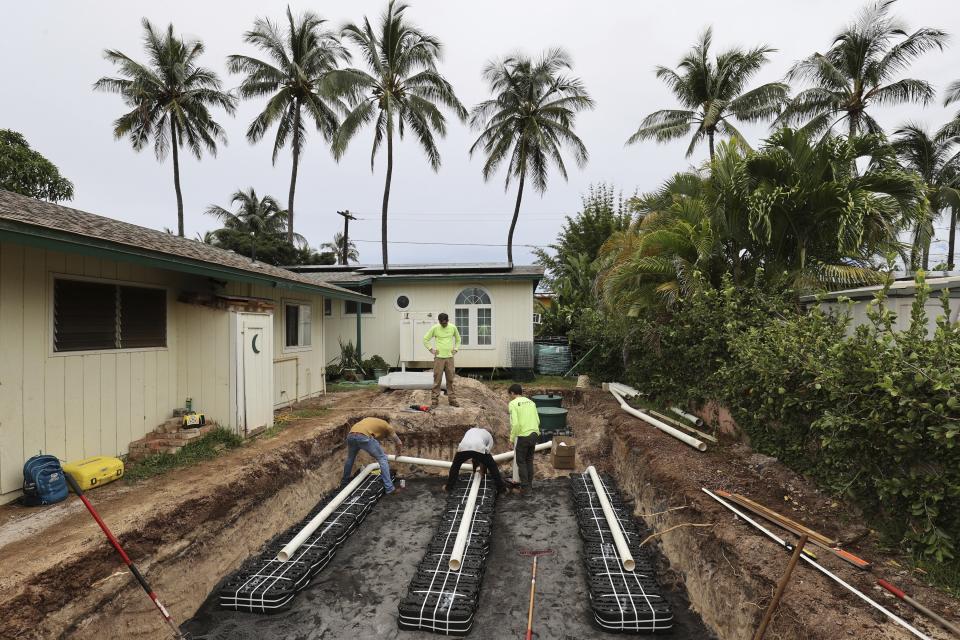 Contractors replace a cesspool with a septic tank and leach field system on Thursday, May 11, 2023, in Waialua, Hawaii. Rising seas are eroding Hawaii's coast near homes with cesspools, pulling sewage out to sea. (AP Photo/Marco Garcia)