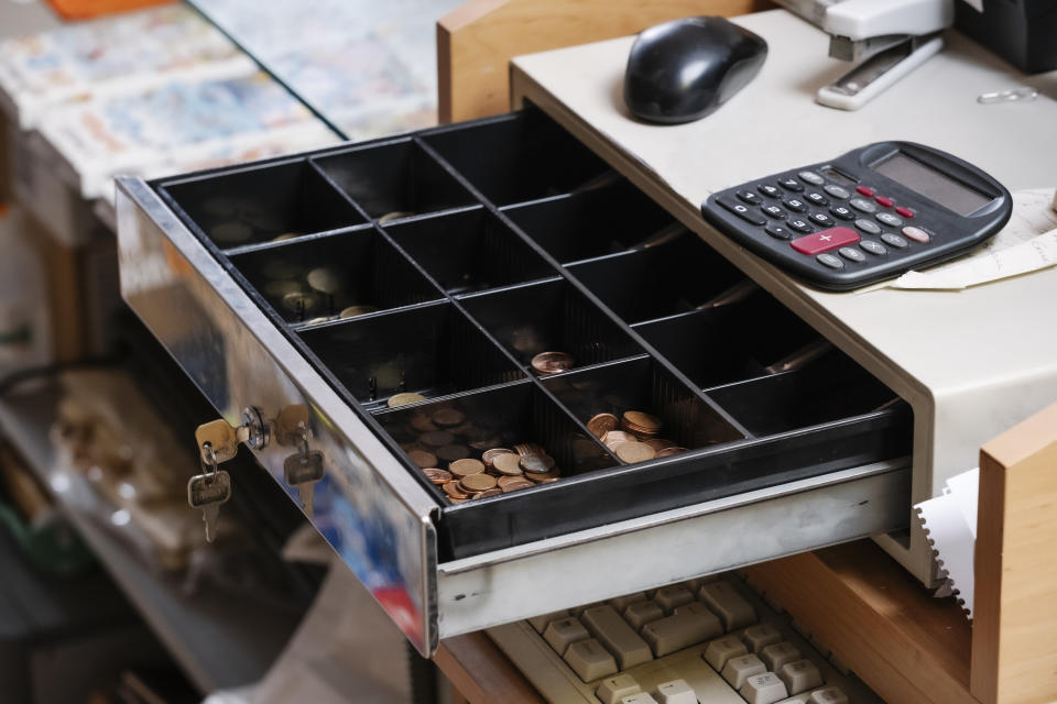A cash register's drawer open showing its money