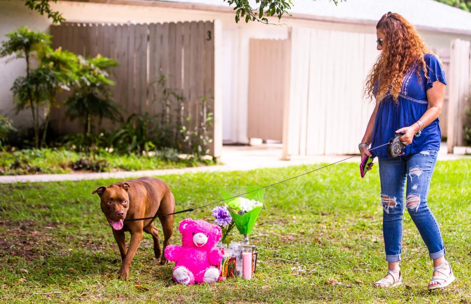 Tammy Cohen walks with her dog Coco near the makeshift memorial for the late  Ajike "AJ" Shantrell Owens at Quail Run, Wednesday afternoon, June 7, 2023 after leaving flowers and a candle.  "I had to come. This story really broke my heart," Cohen said, almost a week after the fatal shooting of Ajike "AJ" Shantrell Owens. Owens was shot while standing outside her neighbor's door the night of June 2 in Quail Run, located off County Road 475A in Ocala. Quail Run consist of single story duplex and quadraplex. Susan Louise Lorincz, 58, now faces charges of manslaughter with a firearm, culpable negligence, two counts of assault and battery. [Doug Engle/Ocala Star Banner]2023