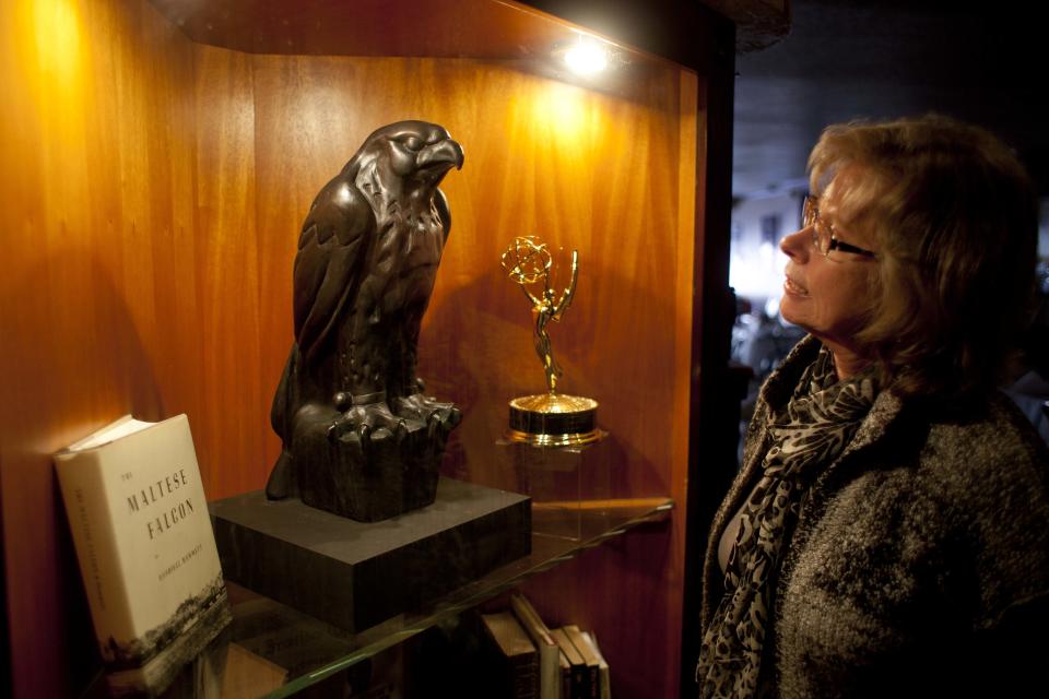 In this photo taken Thursday, Sept. 27, 2012, Gloria Para of San Francisco, looks at a replica of the Maltese Falcon at John's Grill in San Francisco. San Francisco has a long history as a favorite site for filmmakers and the movie buffs who want to see the spots where their favorite scenes took place, from Fort Point under the Golden Gate Bridge where Jimmy Stewart saved Kim Novak in "Vertigo" to the steps of City Hall, where Sean Penn gave an impassioned speech in "Milk," to Alcatraz, stage for Clint Eastwood and many others. One of the city's oldest restaurants, the grill was a setting in author Dashiell Hammett's “The Maltese Falcon.” The interior looks just as you would picture it from the book, filled with original period furnishings. The walls are covered with photos of famous customers and the second floor has a replica of the falcon, along with movie stills and foreign translations of the novel. (AP Photo/Eric Risberg)