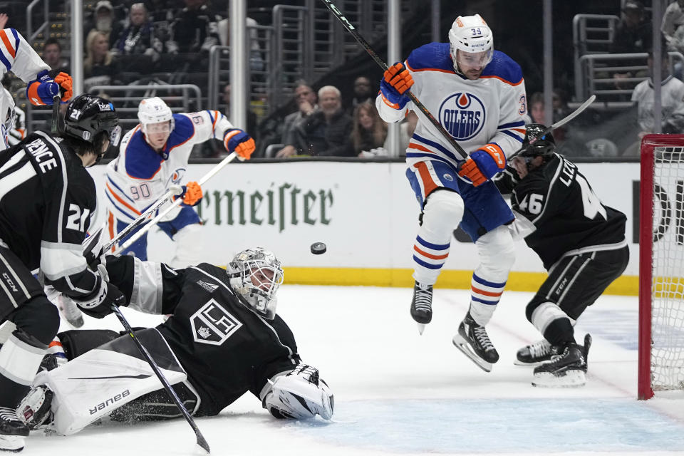The puck flies by Los Angeles Kings goaltender Cam Talbot (39) as Edmonton Oilers center Sam Carrick (39) jumps out of the way while defenseman Jordan Spence (21), right wing Corey Perry (90) and center Blake Lizotte (46) watch during the third period in Game 3 of an NHL hockey Stanley Cup first-round playoff series Friday, April 26, 2024, in Los Angeles. There was no goal on the play. (AP Photo/Mark J. Terrill)