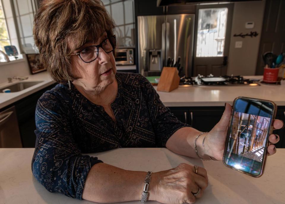 Teri Ostlie holds up a phone with a photo on the screen.