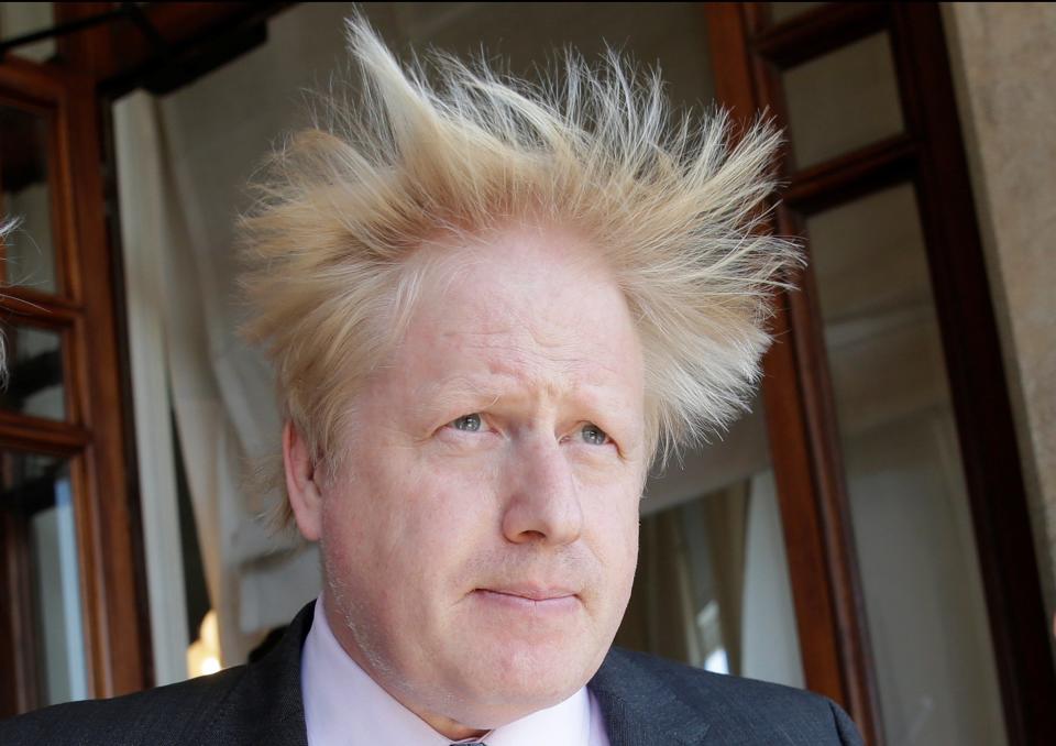 Boris Johnson looks serious but his hair is swept up into the air by the wind - Credit: Max Rossi/Reuters