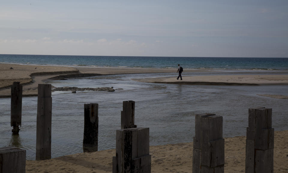 A man walks on Boca Ciega beach where swimming is restricted due to the COVID-19 pandemic in Havana, Cuba, Monday, June 22, 2020. With coronavirus cases down to a handful a day, Cuba is betting on a new form of tourism by designating five keys off its coast as all-inclusive vacation sites almost completely isolated from the rest of Cuba, in an attempt to restart a vital industry without reintroducing the virus to the country. (AP Photo/Ismael Francisco)