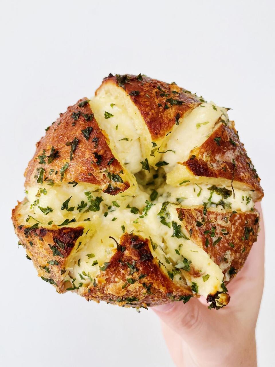 A hand holds up a garlic-butter bagel from Calic Butter from Korean-inspired pop-up Calic Bagels in Westlake L.A.