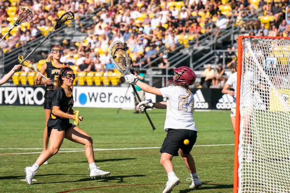 Upper Arlington's Cam Callaghan (4) scores a goal on New Albany goal's Annika Duncan (24) during the Division I state final.
