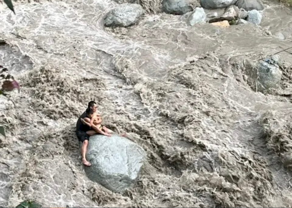 日前中國彭州龍漕溝山洪爆發，在溝中玩水的遊客來不及撤離，多人罹難受傷。圖為一對父子在急流中緊緊相擁避難。(圖：取自微博)