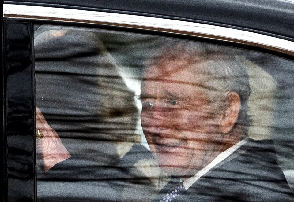 Britain's King Charles III waves as he travels with his wife Britain's Queen Camilla, from Clarence House to Buckingham Palace, in London on February 6, 2024. Britain's King Charles III was on Tuesday seen in public for the first time since his cancer diagnosis was made public a day before. Charles was photographed leaving his residence near Buckingham Palace, with the Press Association news agency reporting he was "believed to be preparing to travel by helicopter to Sandringham", a royal residence in eastern England. (Photo by HENRY NICHOLLS / AFP) (Photo by HENRY NICHOLLS/AFP via Getty Images)