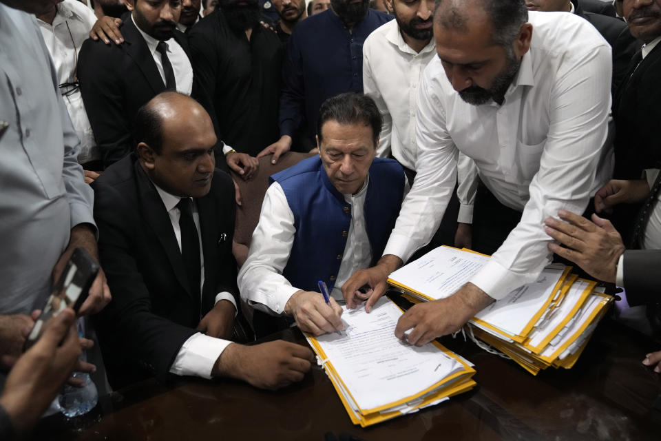 Pakistan's former Prime Minister Imran Khan, sign documents as he submits surety bond over his bails in different cases at an office of Lahore High Court in Lahore, Pakistan, Tuesday, July 18, 2023. (AP Photo/K.M. Chaudary)