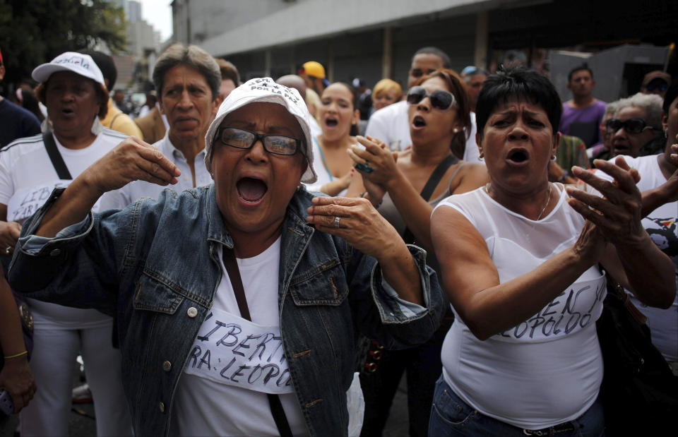 Women wearing white and homemade signs that read in Spanish; "Freedom for Leopoldo," shout slogans in support of opposition leader Leopoldo Lopez outside the Palace of Justice in Caracas, Venezuela, Wednesday, Feb. 19, 2014. Following a dramatic surrender on Tuesday and a night in jail, Lopez is due in court Wednesday to learn what charges he may face for allegedly provoking violence during protests against the socialist government in the divided nation. (AP Photo/Rodrigo Abd)