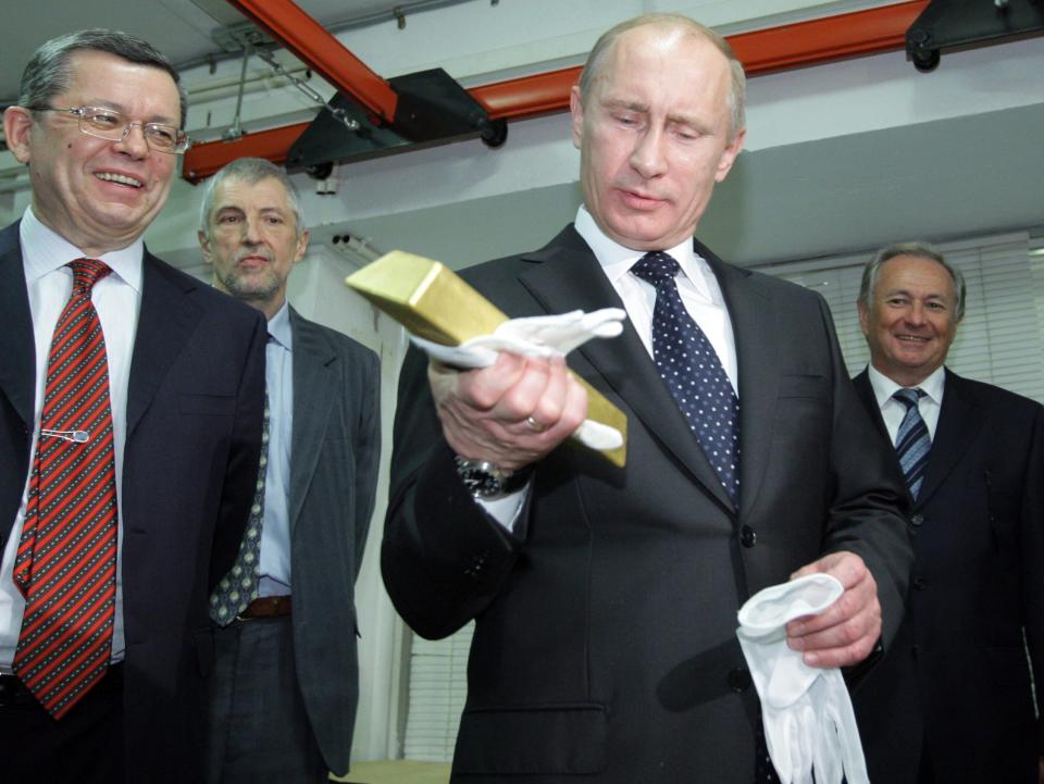 Der russische Präsident Wladimir Putin hält einen Goldbarren während eines Besuchs im Zentraldepot der Russlandbank. Neben Putin steht Georgy Luntowski.