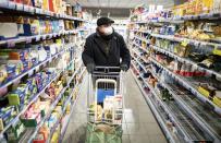 A customer wearing a face mask and gloves goes shopping in the early morning in a supermarket in the Berlin district of Friedenau, Germany, Tuesday, March 17, 2020 In order to slow down the spread of the coronavirus, the German government has considerably restricted public life. Only for most people, the new coronavirus causes only mild or moderate symptoms, such as fever and cough. For some, especially older adults and people with existing health problems, it can cause more severe illness, including pneumonia. (Kay Nietfeld/dpa via AP)