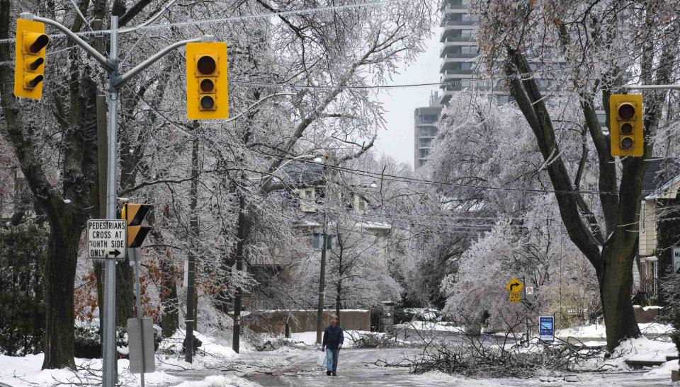 A man walks down the street behind traffic lights with no power following an ice storm in Toronto, December 22, 2013. REUTERS/Mark Blinch (CANADA - Tags: ENVIRONMENT)