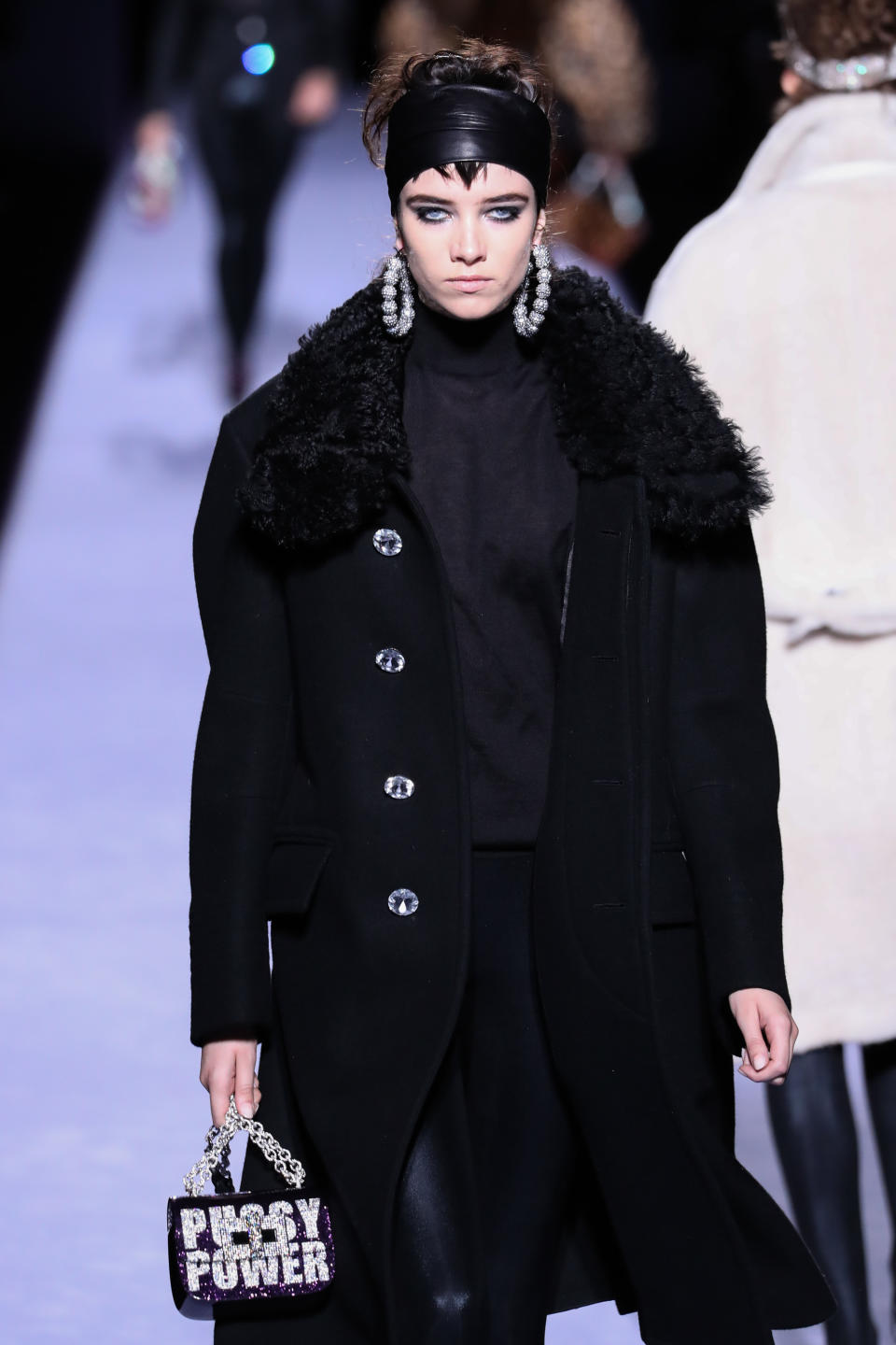 <p>A model carries a shiny bag with a statement at the Tom Ford fall/winter 2018 runway show. (Photo: Getty Images) </p>