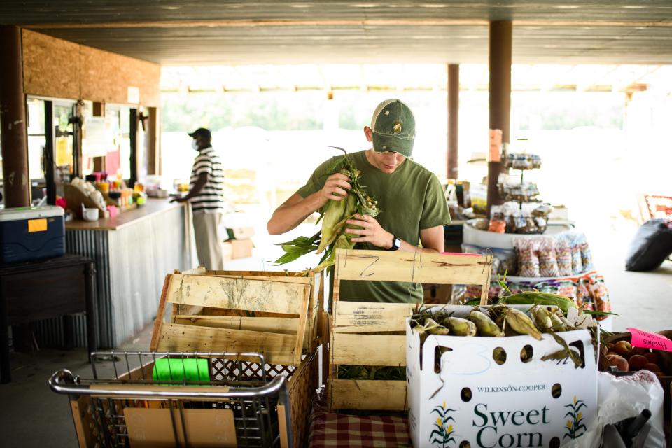 Edward Cook stocks the corn at Gillis Hill Road Produce stand on July 17, 2020.