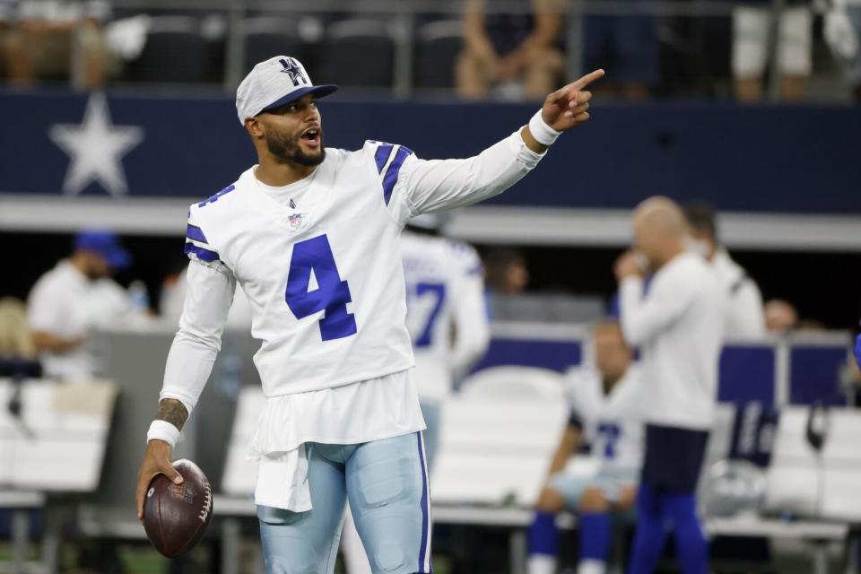 Dallas quarterback Dak Prescott points as warms up before a game in 2021.