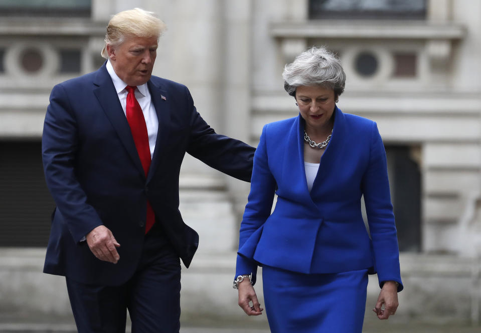 Britain's Prime Minister Theresa May and President Donald Trump walk through the Quadrangle of the Foreign Office for a joint press conference in central London, Tuesday, June 4, 2019. (AP Photo/Frank Augstein)