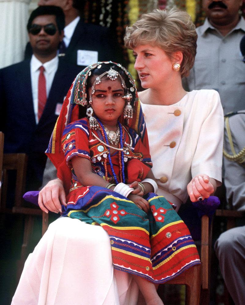 Hats off… A child in traditional costume sits on the Princess of Wales’s lap at Lallapet high school in Hyderabad, India in 1992.