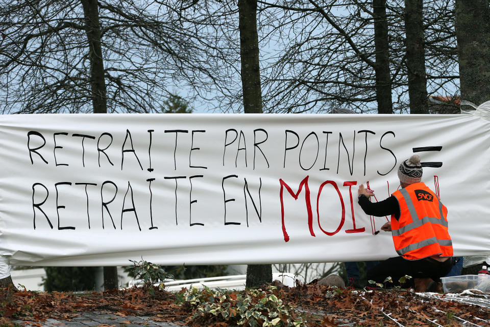 A protester works on a banner " Pensions by points = less pensions", during a demonstration, in Anglet southwestern France, Saturday Dec. 7, 2019. Strikes disrupted weekend travel around France on Saturday as truckers blocked highways and most trains remained at a standstill because of worker anger at President Emmanuel Macron's policies. (AP Photo/Bob Edme)