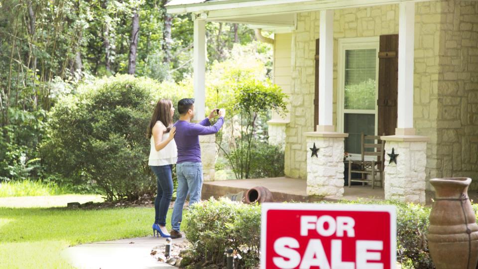 Couple taking picture of home for sale