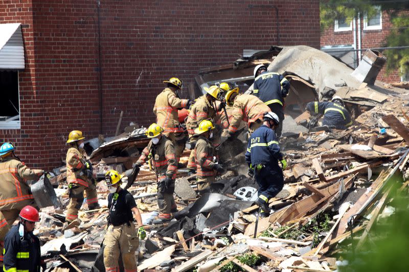 Rescue workers stand on the debris of a destroyed building after an explosion in a residential area of Baltimore