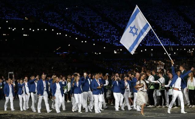 The issue proved a diplomatic headache for IOC President Jacques Rogge, who had hoped to end the debate with a surprise tribute to the victims in the Olympic village in London. Israel's flag bearer Shahar Zubari holds the national flag as he leads the contingent in the athletes parade during the opening ceremony of the London 2012 Olympic Games at the Olympic Stadium July 27, 2012.